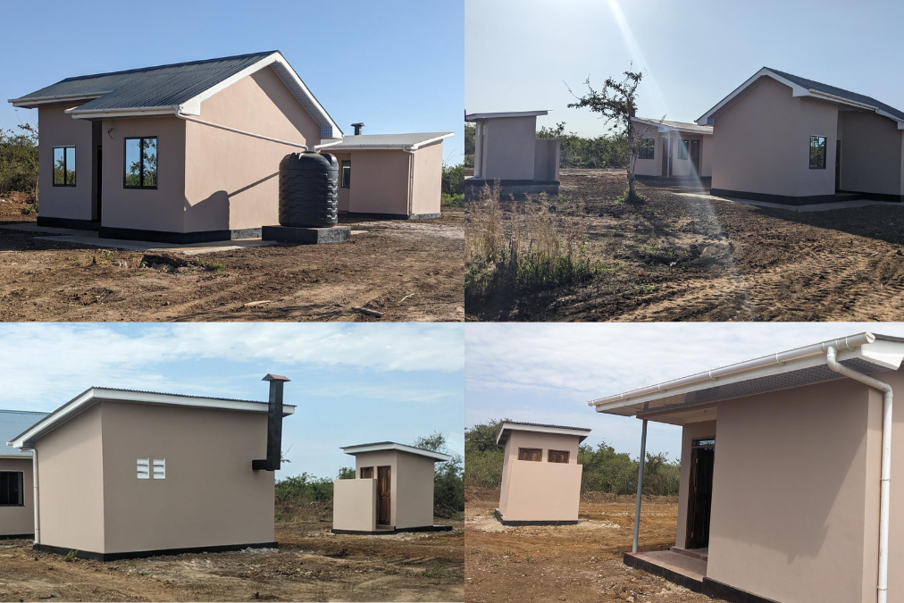 Newly constructed resettlement homes with water tanks and sanitation facilities in a rural landscape